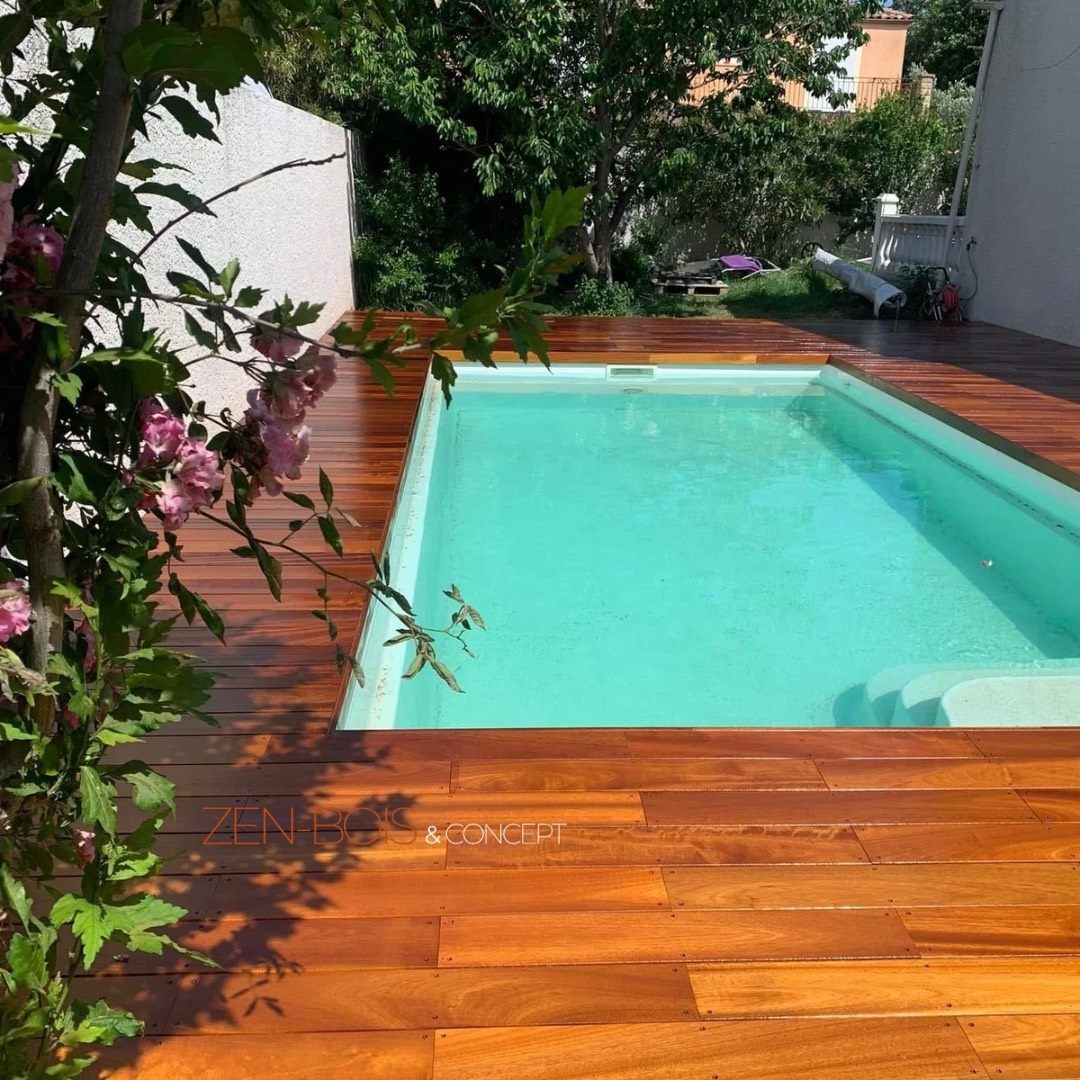 Terrasse en bois exotique en angle autour d’une piscine moderne attenante à une maison contemporaine